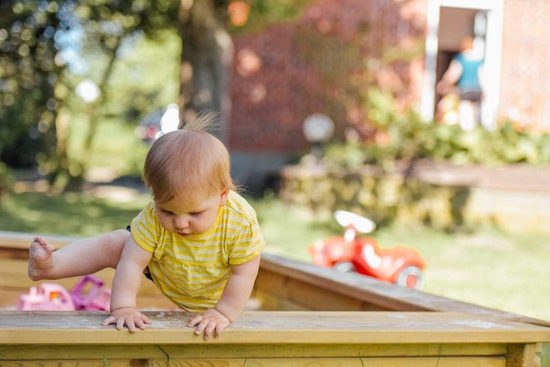 baby climbing out of sandpit